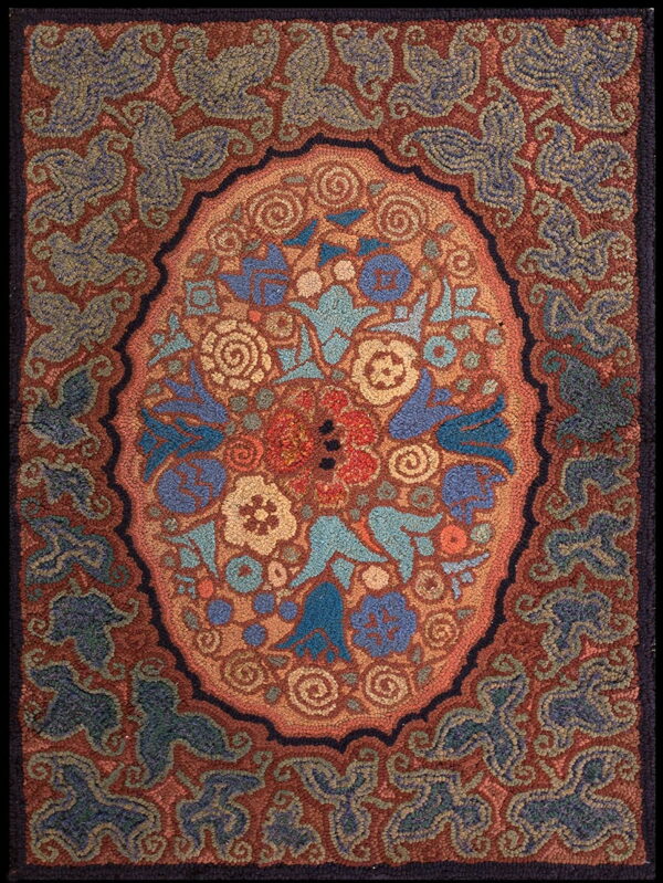 Rustic hooked rug with a central floral medallion pattern in blues, gold, and terracotta.