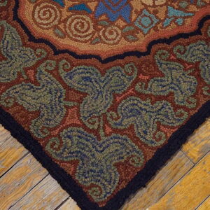 Highly textured rug with rustic floral patterns in rust, green, and blue lies on distressed wood planks.