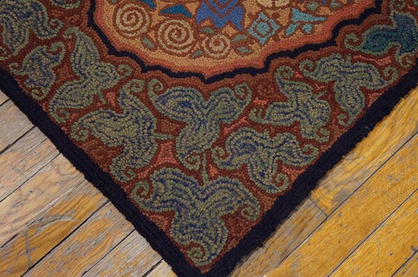 Highly textured rug with rustic floral patterns in rust, green, and blue lies on distressed wood planks.