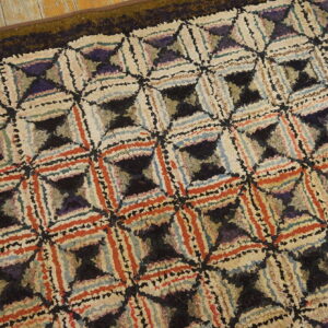 Shaggy, multicolor rug featuring interlocking geometric designs sits on a distressed wood floor.