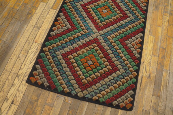 A rectangular rug with a colorful textured scallop pattern rests on light wood plank flooring.
