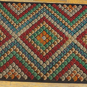 Multicolored rug with a textured scalloped pattern arranged in diagonal stripes on wood flooring.