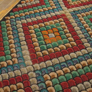 Jewel-toned, high-pile rug with a scalloped pattern organized into concentric squares on light wood planks.