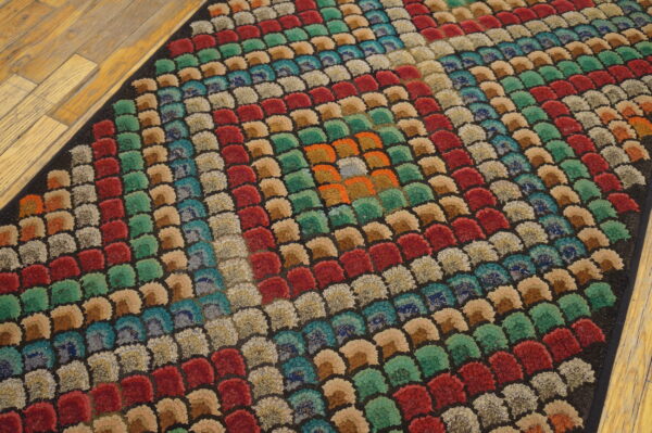Jewel-toned, high-pile rug with a scalloped pattern organized into concentric squares on light wood planks.