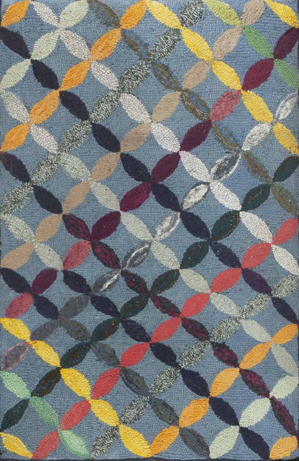 Hooked rug with an interlocking, multicolored geometric pattern over a blue loop pile field.