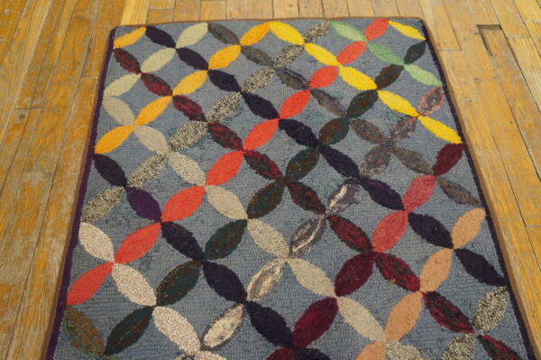 Textured blue rug featuring an interlocking multicolored oval pattern, visible on rustic wood flooring.