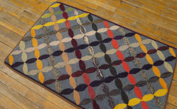 Hooked rug with an all-over multicolored ovals pattern on a blue-gray field over wood flooring.
