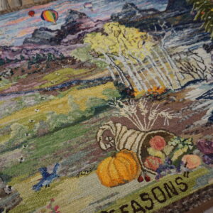 Textured, multicolored area rug featuring a detailed mountain landscape with trees, hot air balloons, and a pumpkin.