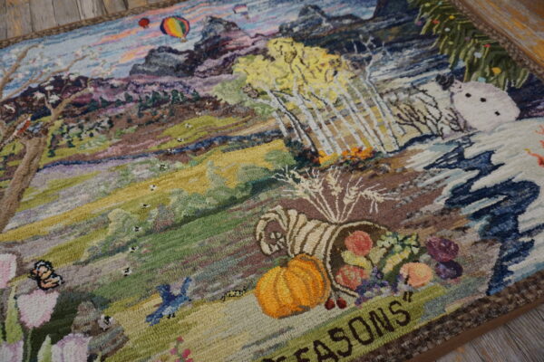 Textured, multicolored area rug featuring a detailed mountain landscape with trees, hot air balloons, and a pumpkin.