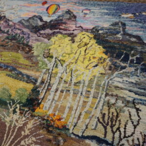 Textured multicolored rug depicting a detailed landscape scene with yellow trees, mountains, and hot air balloons.