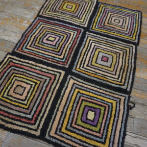 High pile rug with multicolored concentric squares in six blocks rests on rustic wood flooring.