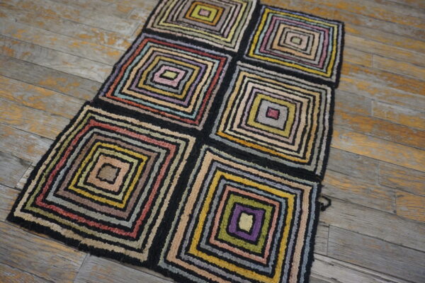High pile rug with multicolored concentric squares in six blocks rests on rustic wood flooring.