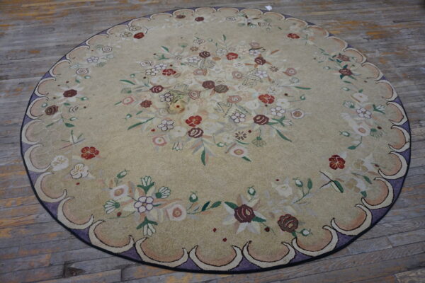 Light beige round rug featuring a multicolored floral pattern and a scalloped lavender border on distressed wood planks.