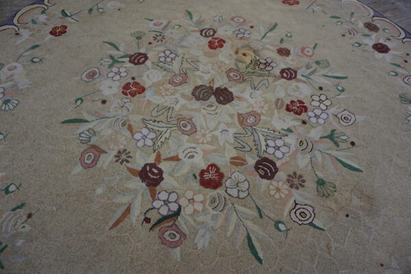 Close-up of a beige textured rug with a central bouquet of red, purple, pink, and green stylized flowers.