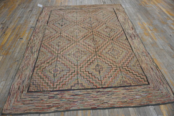 Multicolored textured rug with a central zigzag geometric pattern and wide striped border on distressed wood flooring.