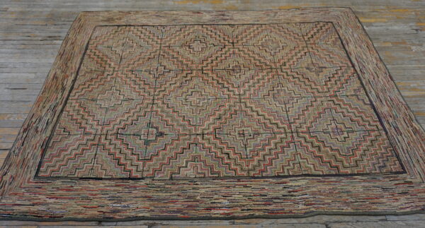 A textured rug with a repeating geometric zigzag pattern is displayed on rustic gray wood plank flooring.