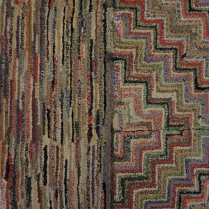 Close-up of a multicolored textured rag rug featuring vertical stripes and a bold chevron pattern.