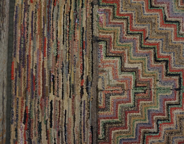 Close-up of a multicolored textured rag rug featuring vertical stripes and a bold chevron pattern.