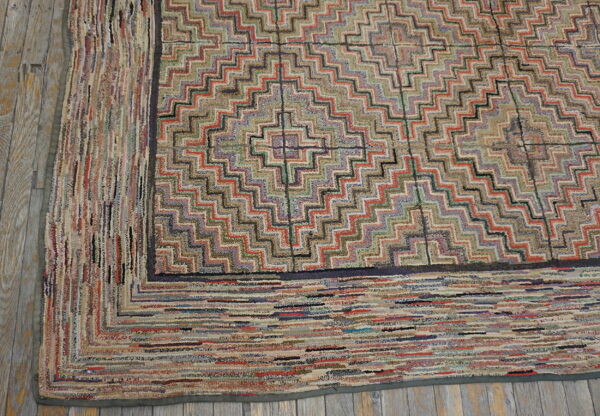 Multicolored geometric rug with a zigzag pattern and thick striped border on rustic wooden floorboards.
