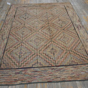 Muted multicolor zigzag patterned rug with a wide textured border laying on rustic wood planks.