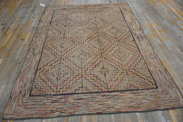 Muted multicolor zigzag patterned rug with a wide textured border laying on rustic wood planks.