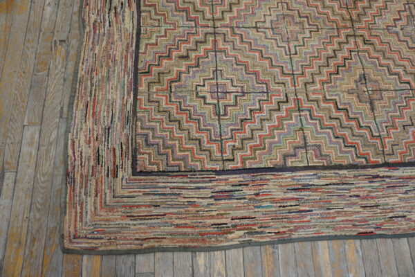 Highly textured, multicolored rug featuring a stepped diamond pattern rests on distressed wood flooring.