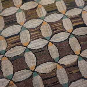 Textured rug with interlocking beige oval shapes and teal accents on a dark striped brown background.