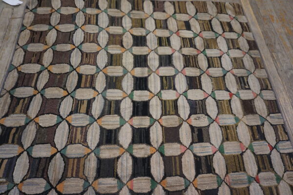 Textured, high-pile rug featuring interlocking cream and multicolored dark geometric patterns on wood floor.