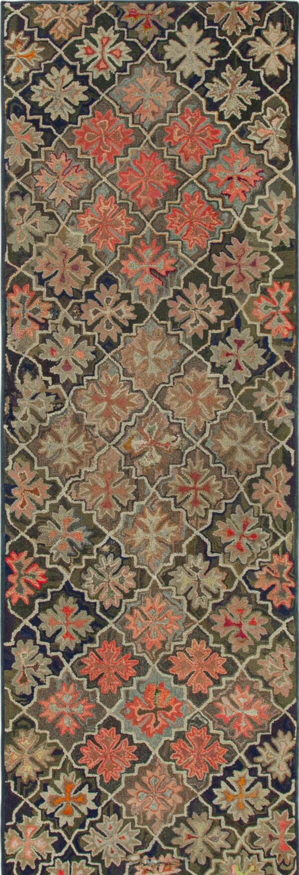 Muted olive and orange floral pattern runner displayed on distressed grey and yellow wood floors next to rolled rugs.