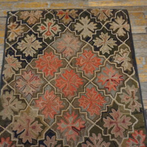 Textured rug with dark green, rust, and tan flowers inside an interlocking trellis on weathered wood planks.