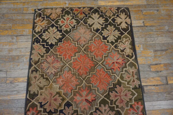 Textured rug with dark green, rust, and tan flowers inside an interlocking trellis on weathered wood planks.