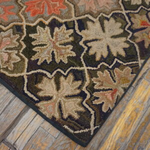 Textured rug in green, beige, and terracotta floral patterns against a weathered wood plank floor.