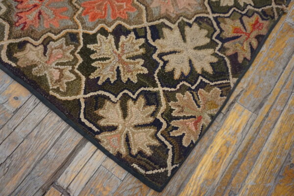 Textured rug in green, beige, and terracotta floral patterns against a weathered wood plank floor.
