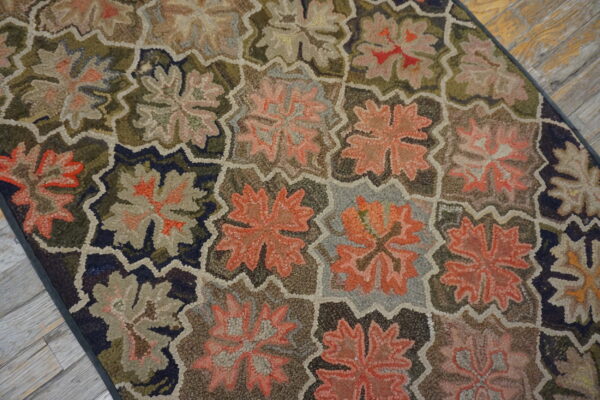 Looped rug featuring large floral motifs in earthy coral and green tones, resting on weathered wood.