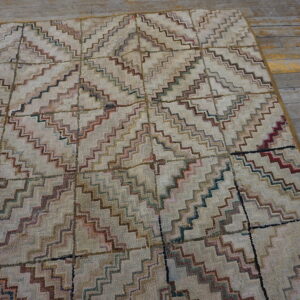 Beige shaggy rug with multicolored zigzag lines creating a grid pattern on weathered wood flooring.