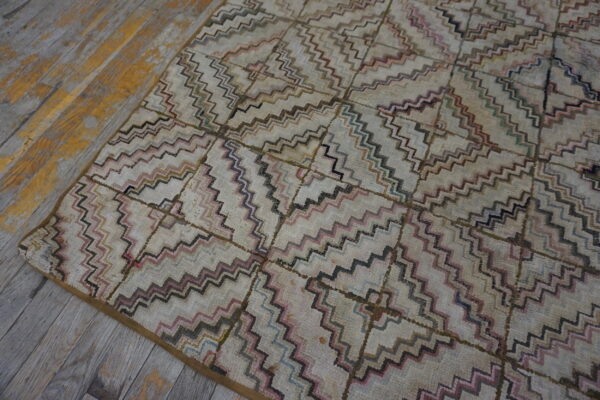 Geometric cream rug featuring multi-colored zigzags and squares lies on weathered wood floorboards.