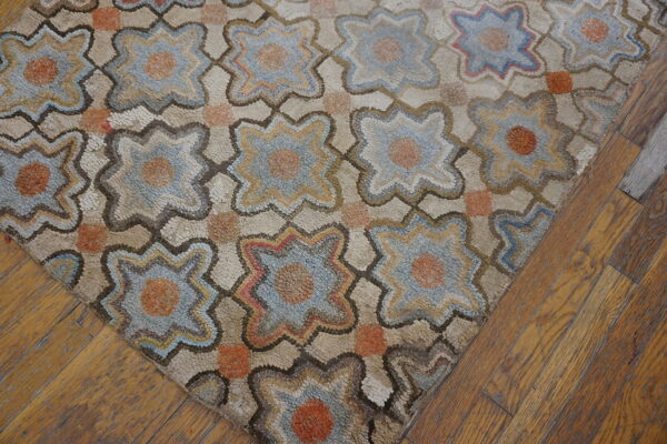 A high-texture rug with blue and orange quatrefoil motifs lies on warm, distressed wood flooring.