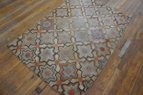 Chunky textured rug with faded blue and orange geometric star patterns rests on a rustic wood floor.