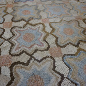 Textured rug with varied pile, showing interlocking star shapes in beige, blue, peach, and brown outlines.