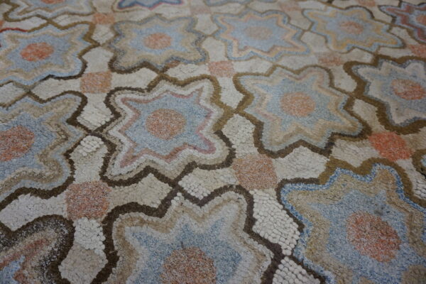 Textured rug with varied pile, showing interlocking star shapes in beige, blue, peach, and brown outlines.
