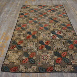 A textured brown rug with alternating geometric and colorful leaf blocks lays on weathered wood flooring.
