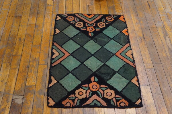 Small rug featuring a green diamond lattice and orange floral designs on distressed wood planks.