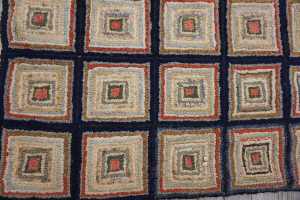 Multicolored hooked rug featuring chunky, concentric log cabin squares separated by a navy blue grid.
