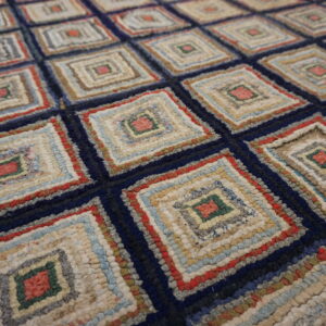 Close-up of a high-texture rug with a repeating diamond pattern in navy, cream, red, green, and light blue.