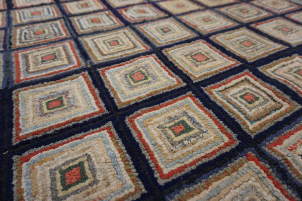 Close-up of a high-texture rug with a repeating diamond pattern in navy, cream, red, green, and light blue.