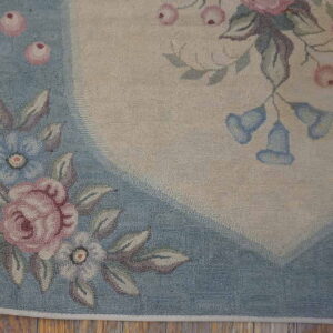 Floral hooked rug on hardwood floor, showing pink roses and blue blossoms on a pale blue border.