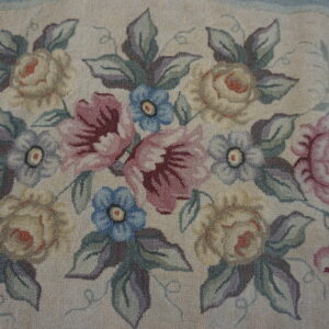 Muted floral rug with a cream background, dusty rose, blue, and pale yellow flowers, and looped texture.