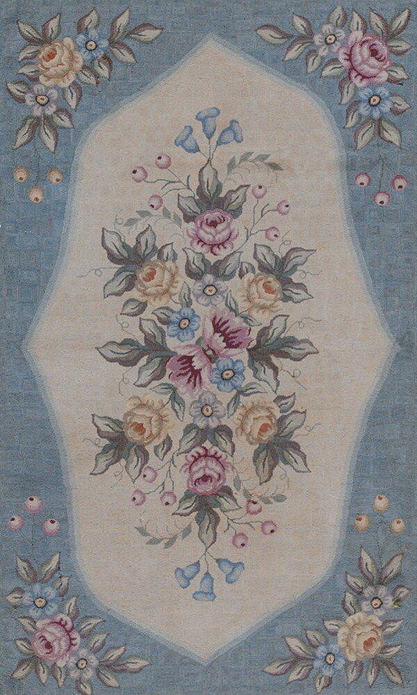 Low pile rug with an ornate pastel floral bouquet inside a cream medallion on a light blue ground.
