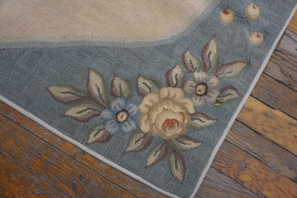 A textured rug border in dusty blue and cream displays a floral pattern on rustic wood floorboards.