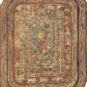 Hooked oblong rug in rich earthy colors with a floral center surrounded by detailed concentric striping.